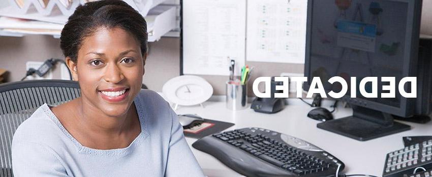 Dedicated text over woman smiling sitting at desk with computer on it.